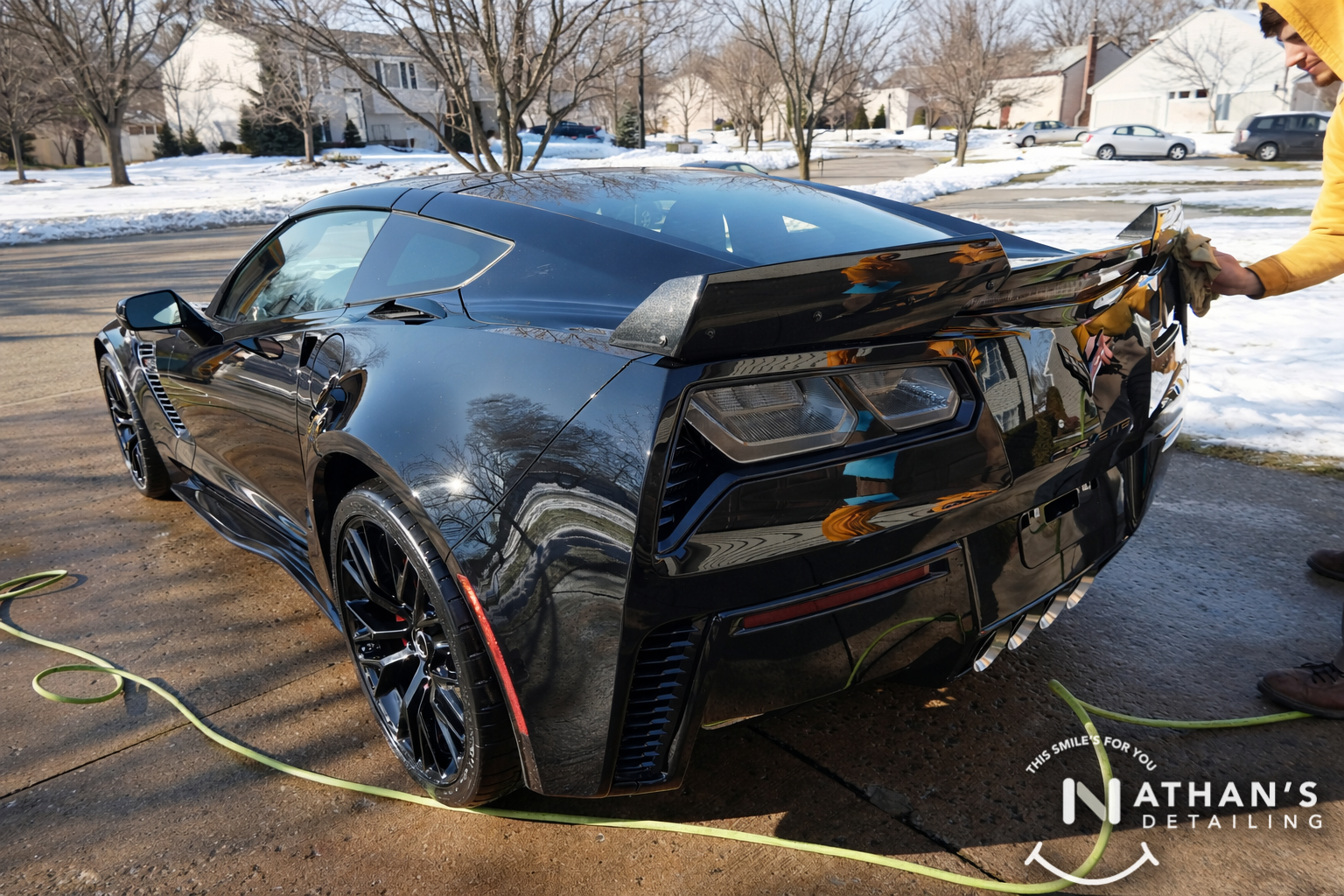 Technician wiping black sports car rear panel during mobile detailing in Kent