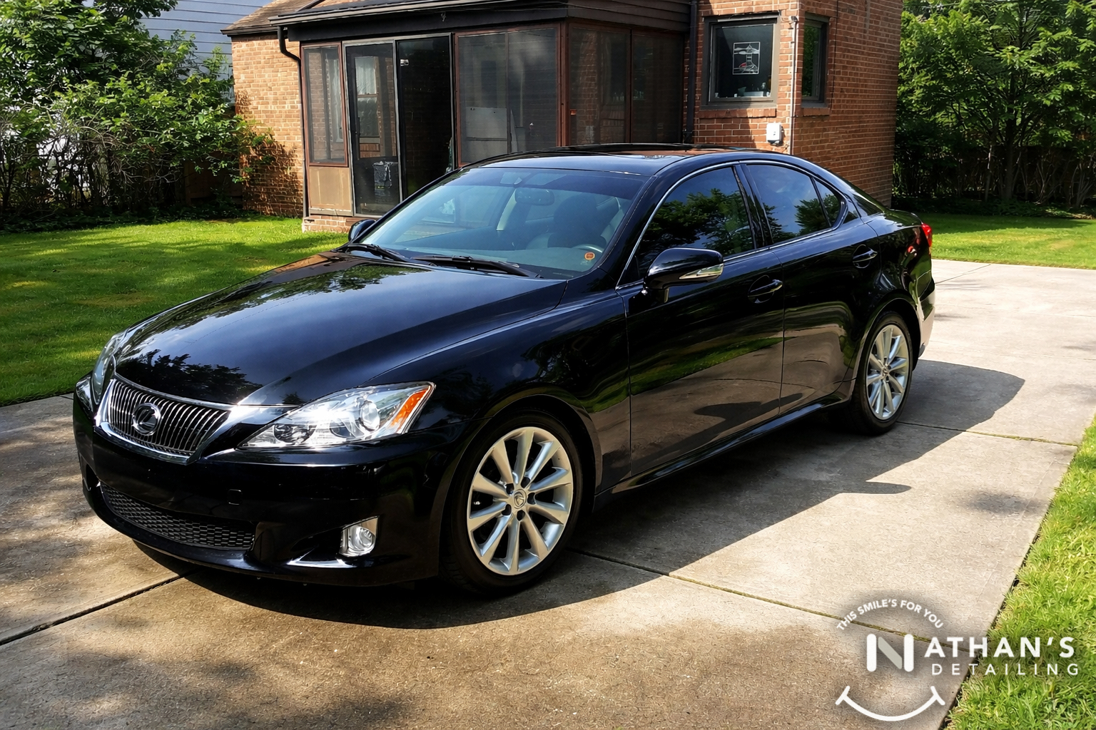 Black sedan glossy finish in driveway during mobile detailing