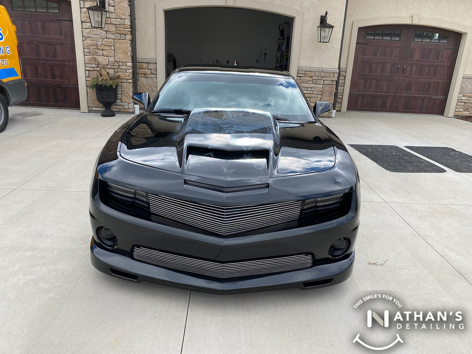 Clean black coupe front view in driveway during mobile detailing in Independence