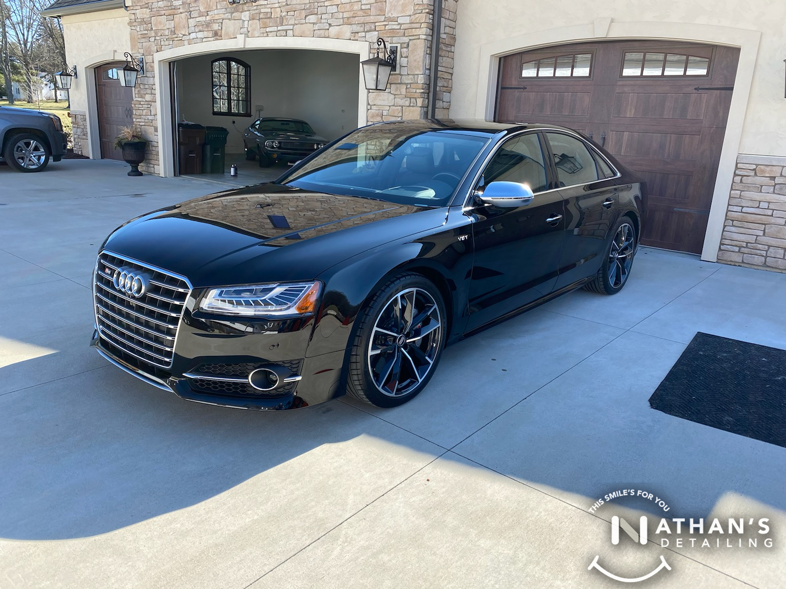 Detailed black sedan parked outside garage during mobile detailing