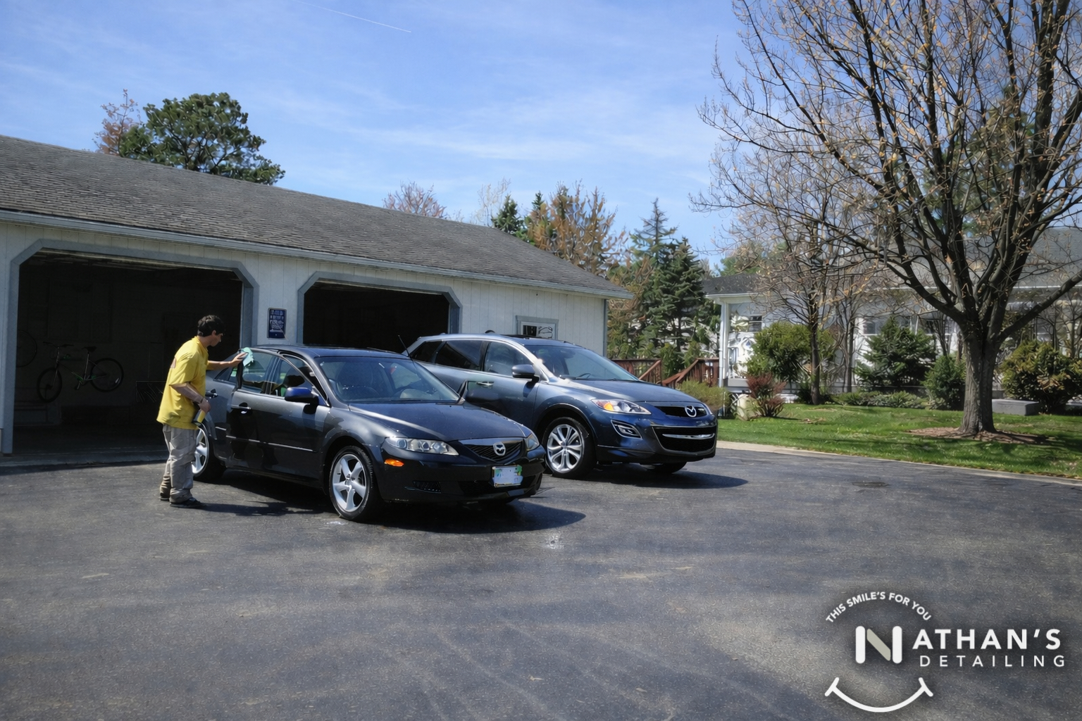Detailer wiping sedan in driveway during mobile detailing
