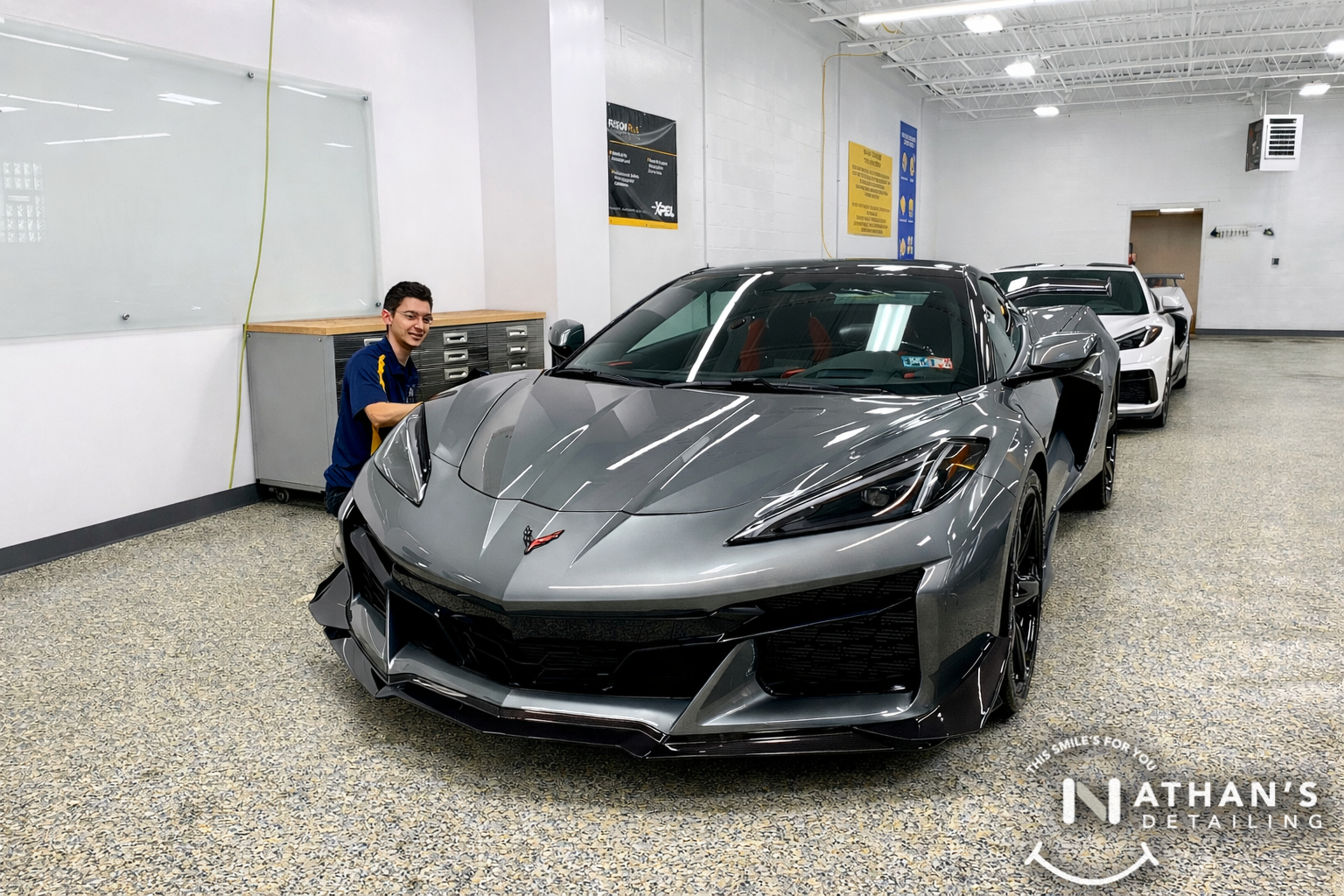 Detailer standing beside a gray Corvette prepared for ceramic coating service.