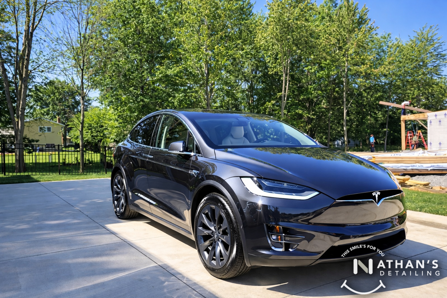 Glossy black tesla suv front angle during mobile detailing