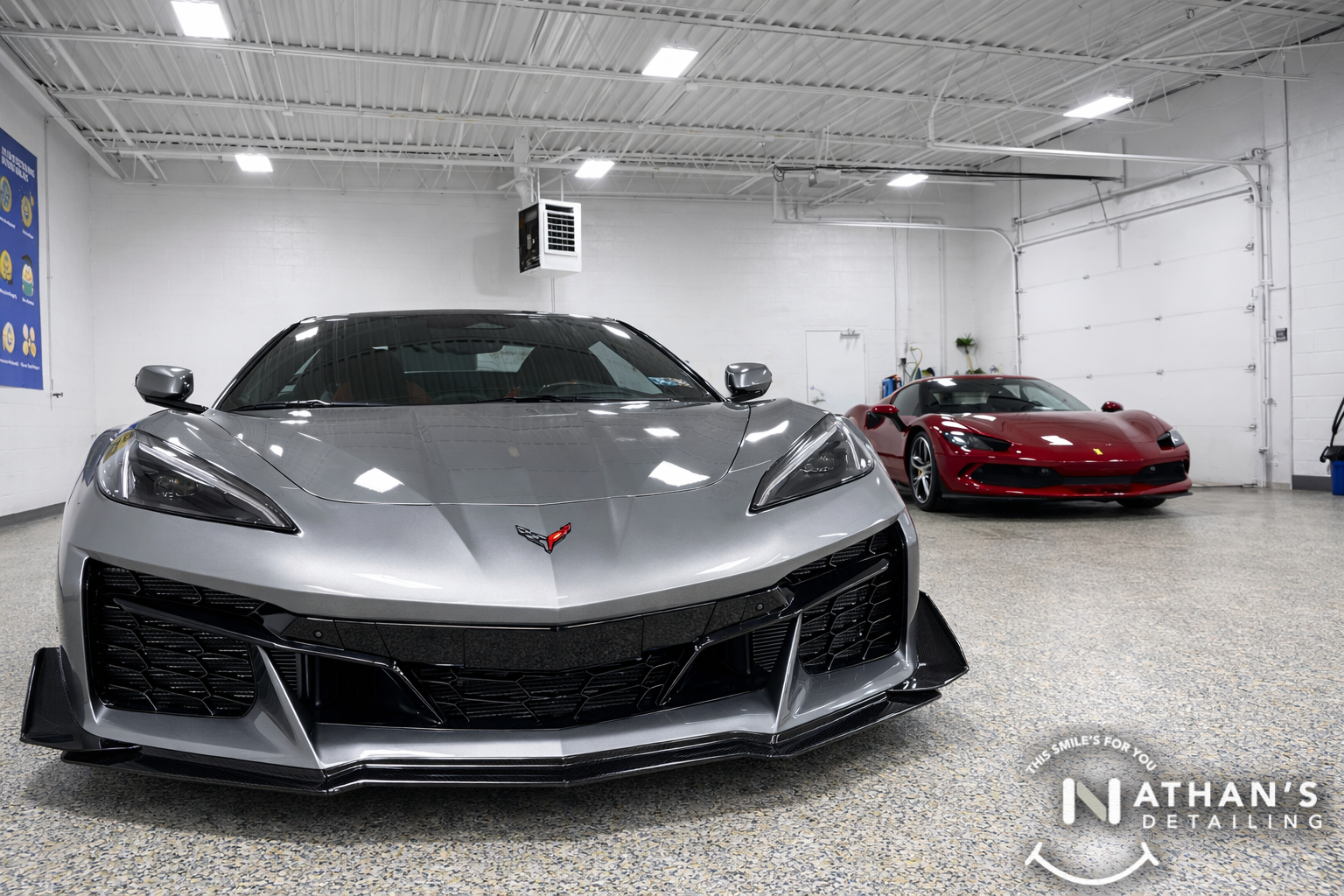 Gray Corvette and red Ferrari parked indoors with polished, ceramic-coated shine.