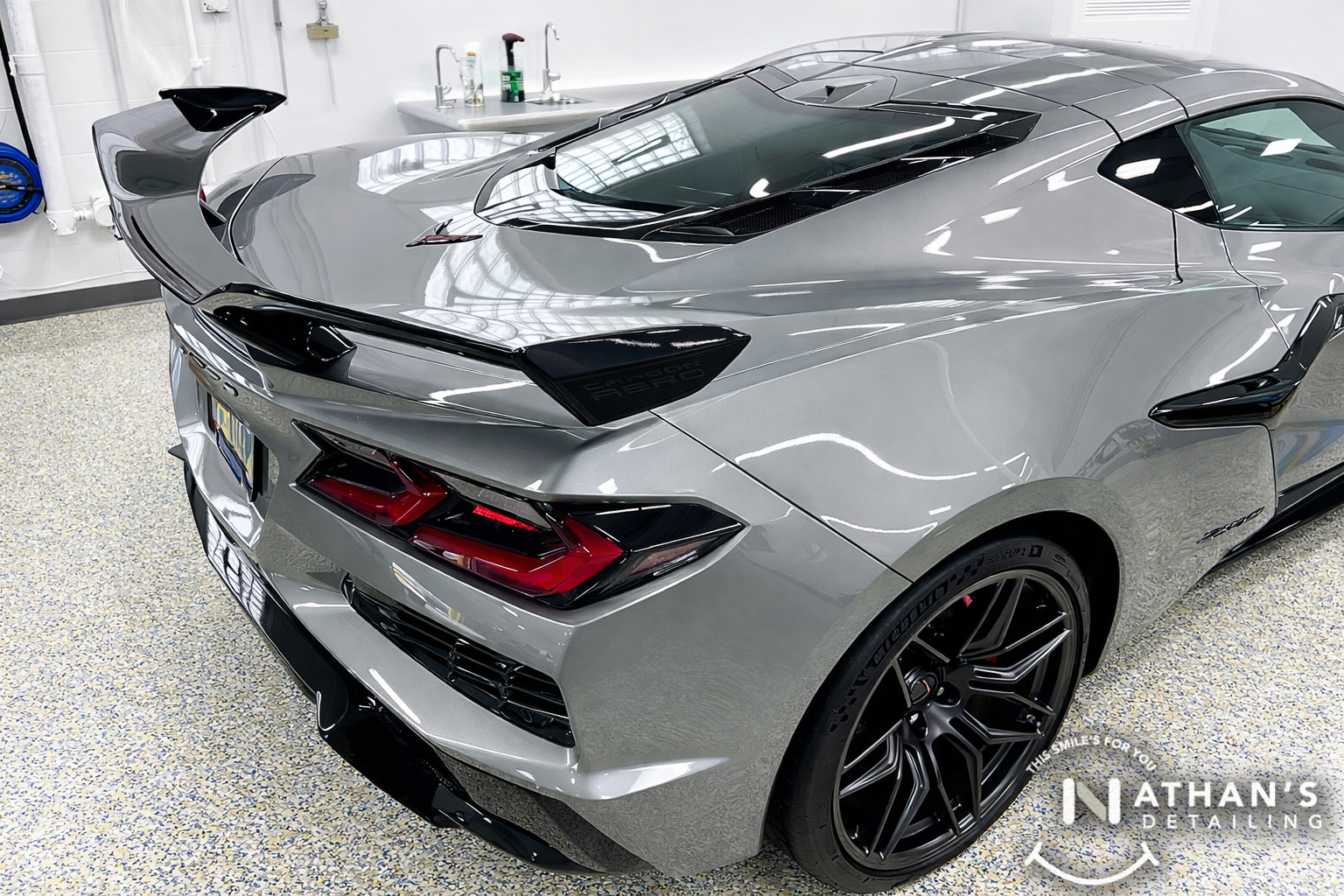 Rear view of a gray Corvette with spoiler and glossy ceramic-coated finish.