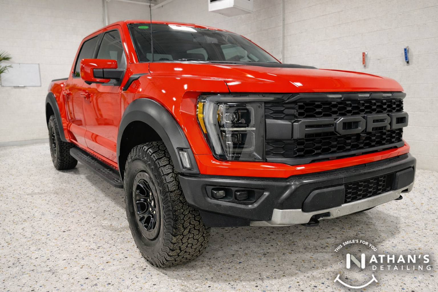 Red Ford Raptor pickup shown indoors with a clean, glossy ceramic-coated finish.