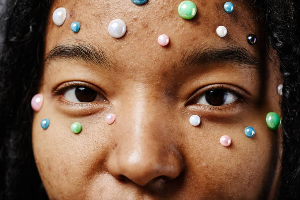 Close-up of a woman's face with colorful pearl decorations on her skin