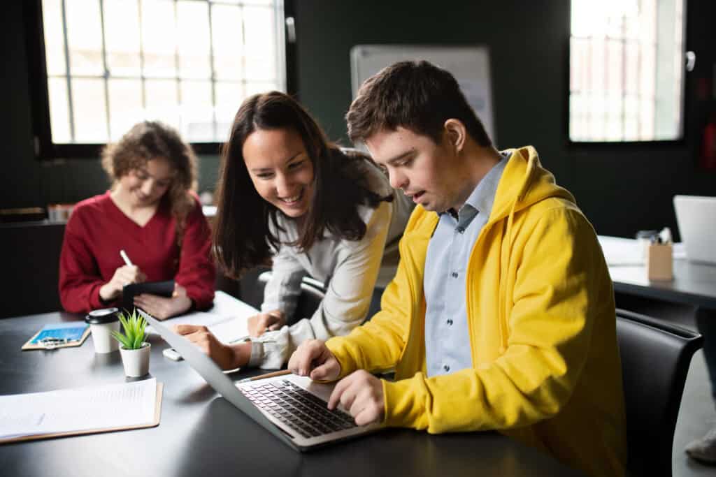 A man with Down syndrome learning with a tutor in a classroom.