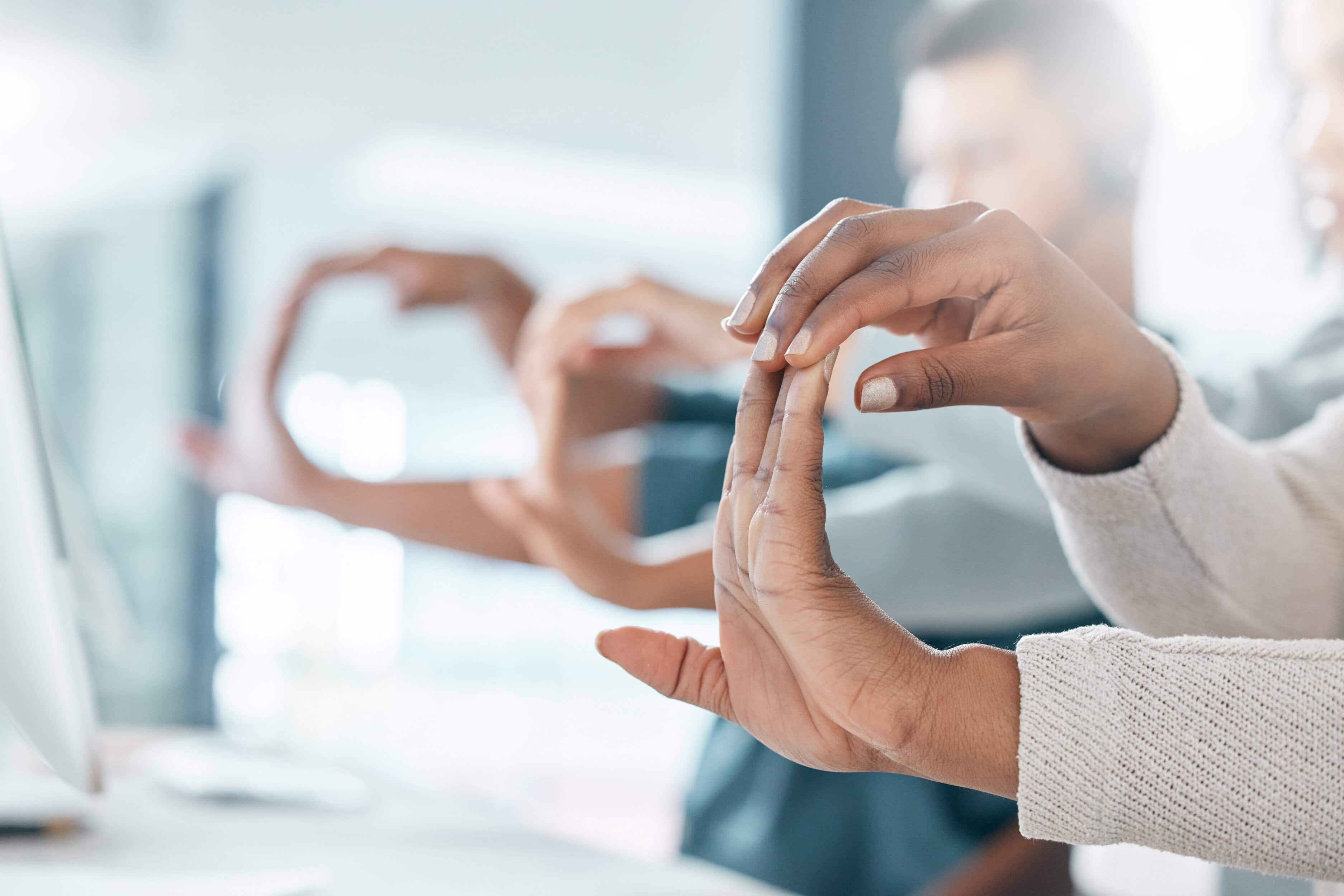 Hands of office workers stretching fingers during a workplace wellness break.