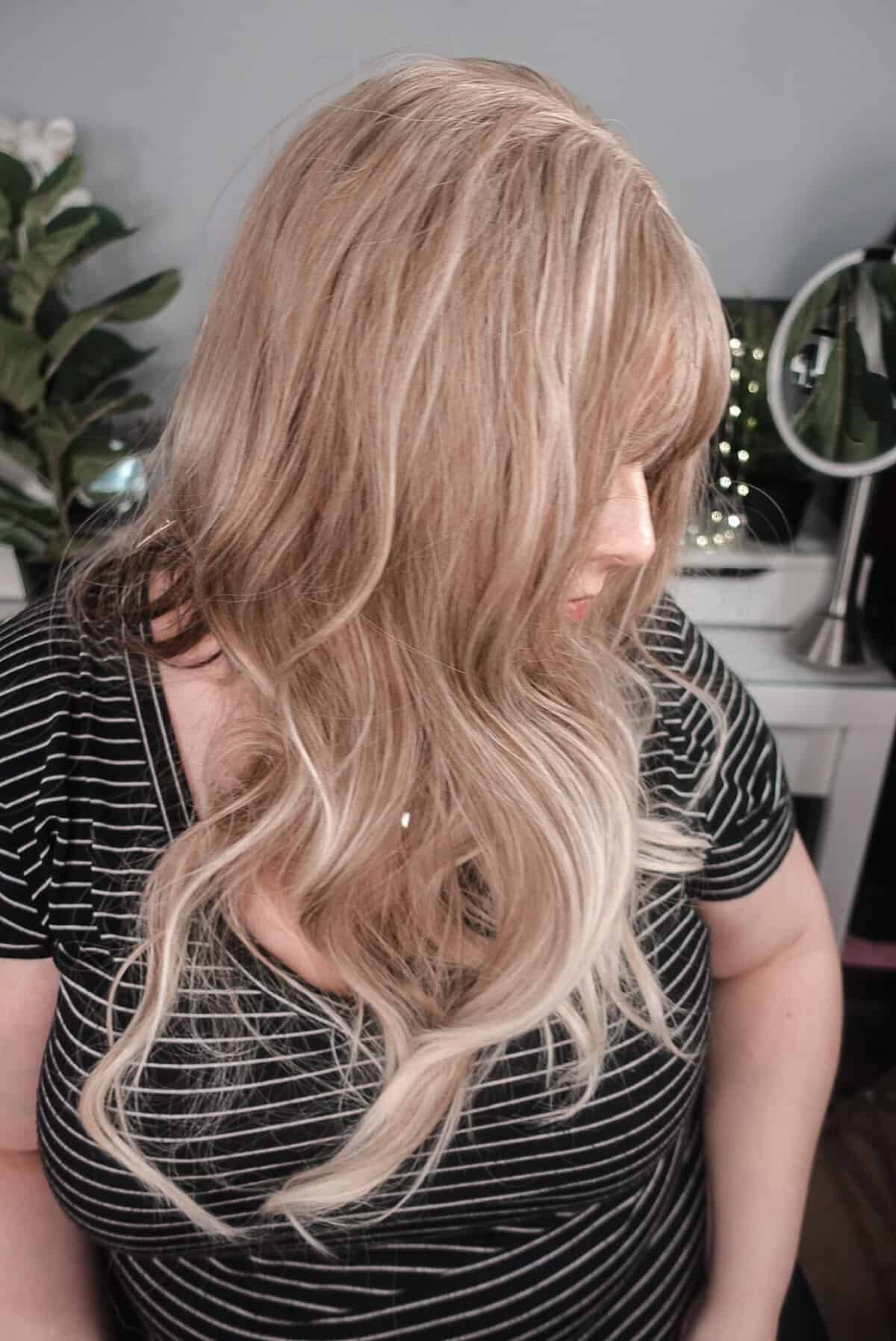 Haircube blonde synthetic wig side view - long wavy with curtain bangs, worn by Neveen Wood