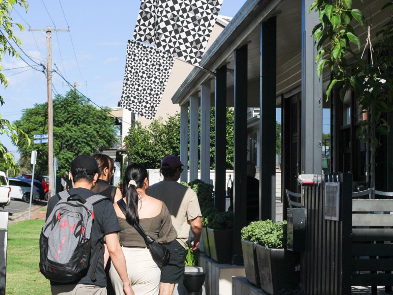 Group of tourists exploring a city street during a country town tour, enjoying local sights and architecture.
