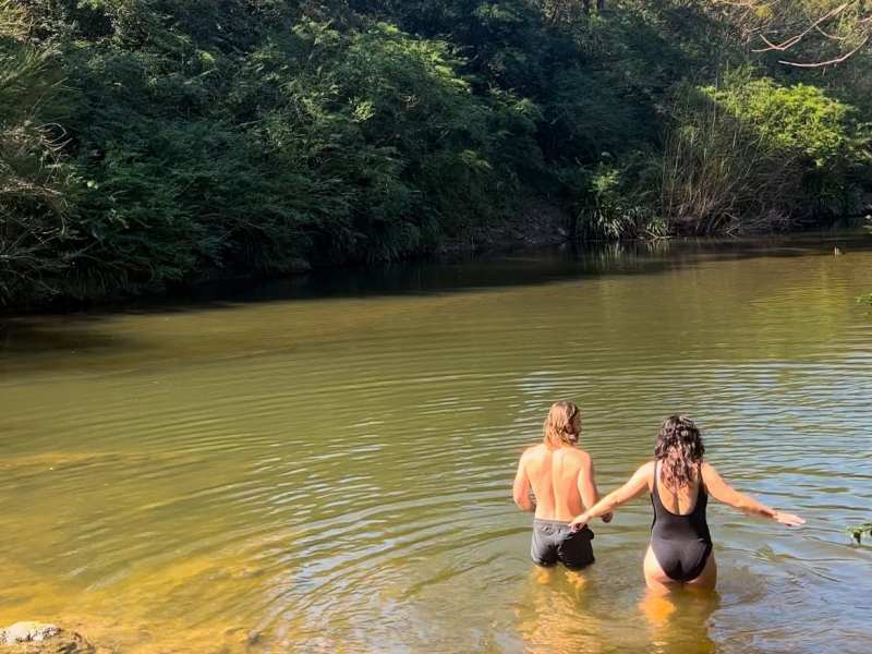 Scenic river view with two women enjoying a peaceful moment in the water during a country town river and farm tour.