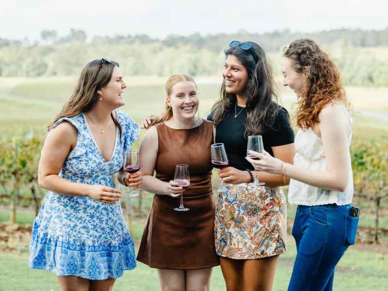 Elegant women enjoying wine tasting at a scenic vineyard, highlighting Newy Tour Co.’s premium winery tours in New South Wales, Australia. Perfect for those seeking a guided wine experience.