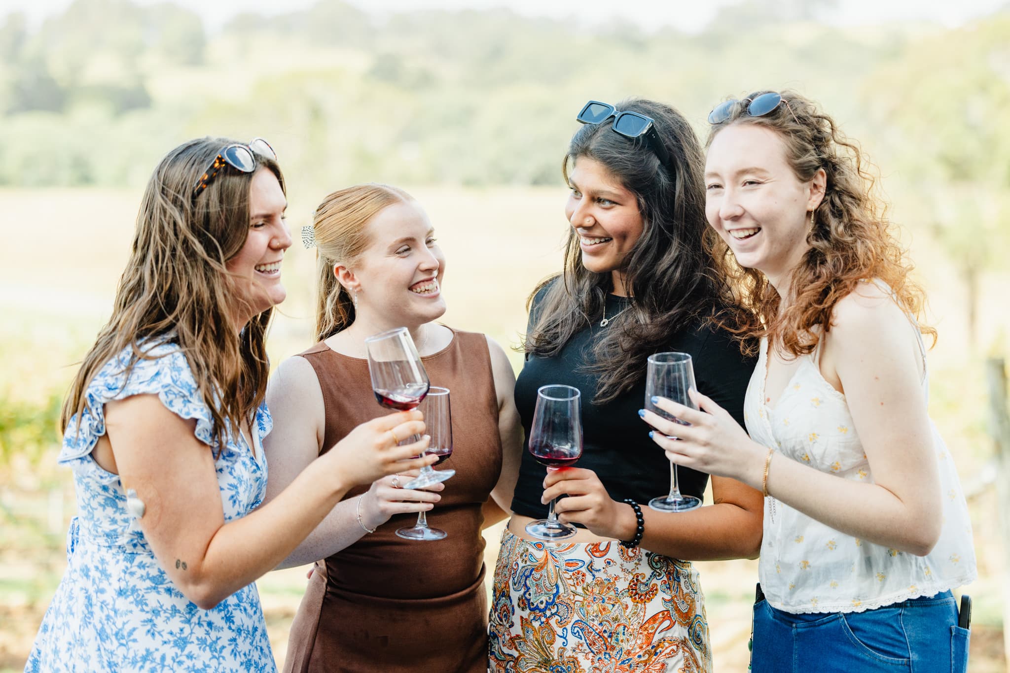 Elegant women enjoying wine tasting outdoors on a sunny day, highlighting Newy Tour Co.'s local wine tours and hospitality services in Newcastle.