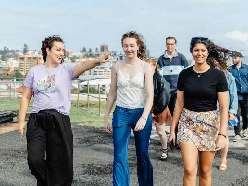 Girl tour guide showing group of diverse friends during city sightseeing tour in Newcastle, Australia.