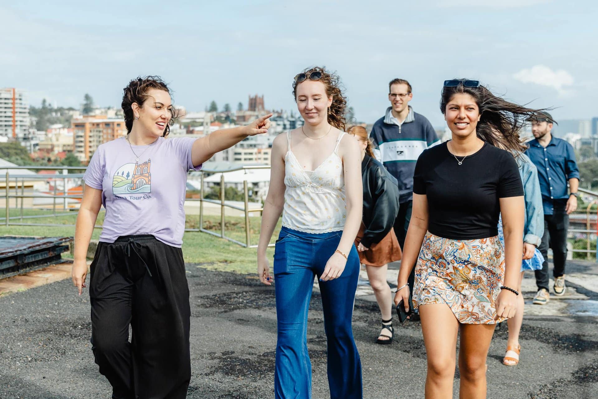 Girl tour guide showing group of diverse friends during city sightseeing tour in Newcastle, Australia.
