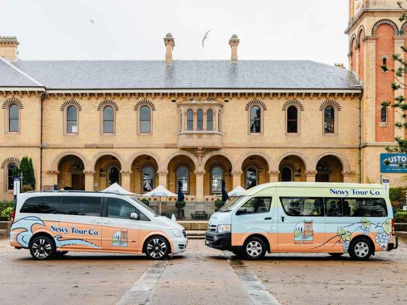 Luxury tour vans parked in front of historic building in Newcastle, Australia, showcasing Newy Tour Co. transportation services for wine tours, city sightseeing, and winery visits.