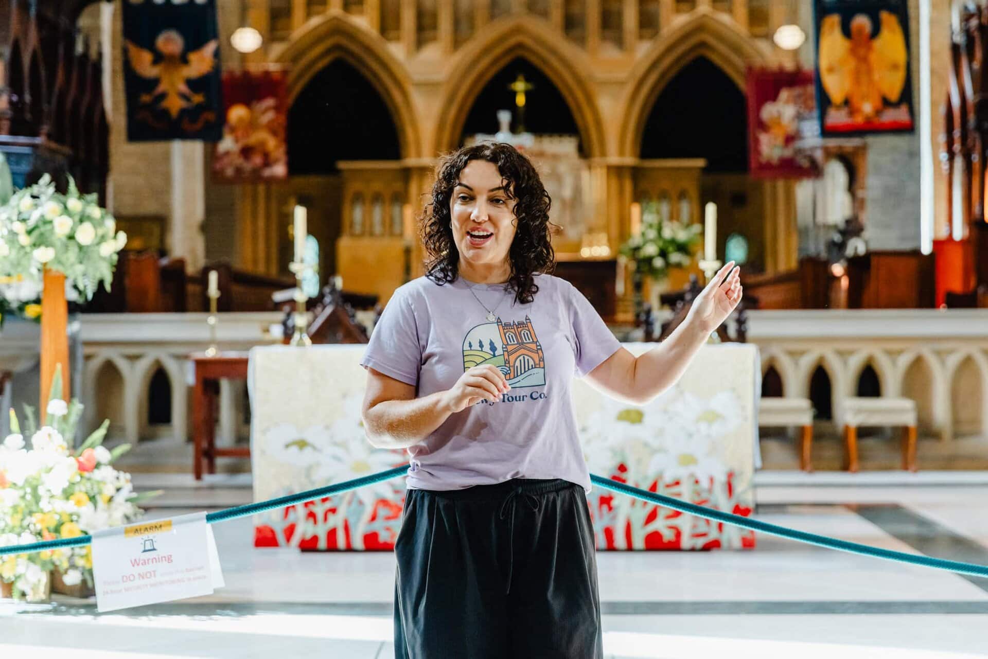 Tour guide in a church, providing local tour insights, dressed in casual attire with Newy Tour Co. logo, inside Newcastle's historic Anglican Cathedral, offering engaging cultural experiences for tourists.