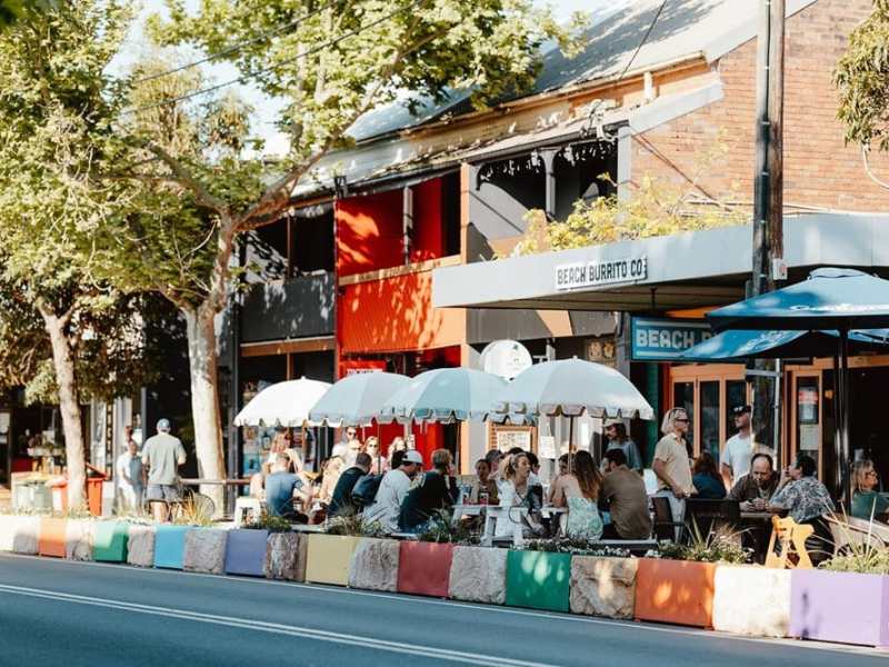 Beach Burrito Co. outdoor seating with people enjoying meals under umbrellas.