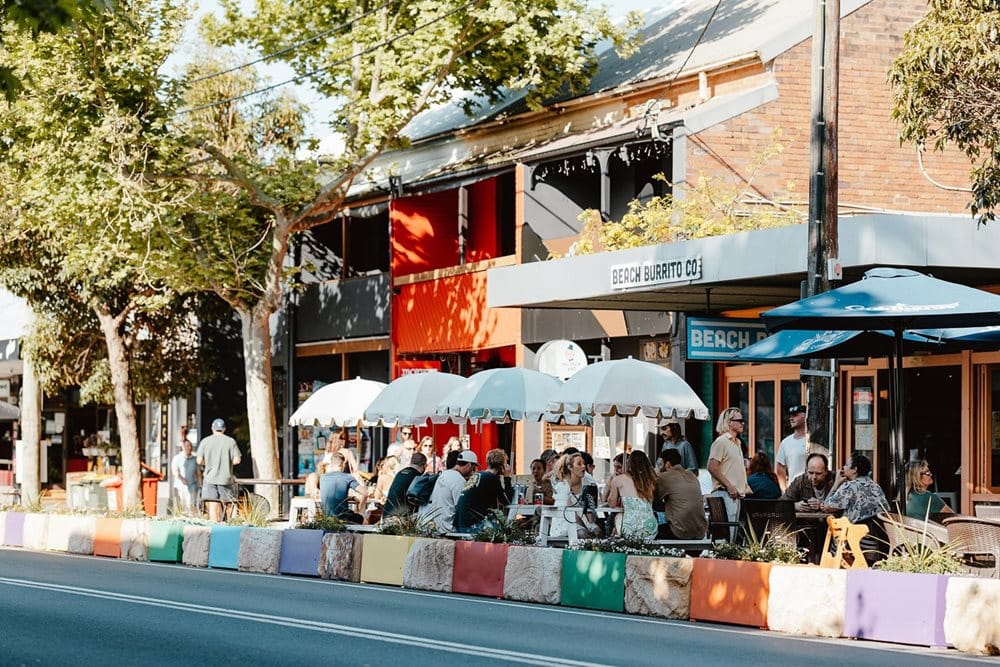 Beach Burrito Co. outdoor seating with people enjoying meals under umbrellas.