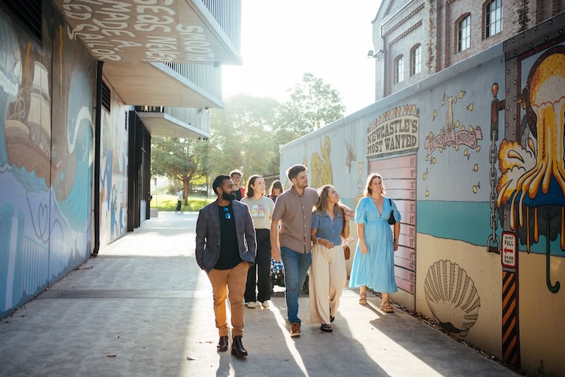 Group of tourists exploring Newcastle's vibrant street art scene and local food spots on a guided tour.