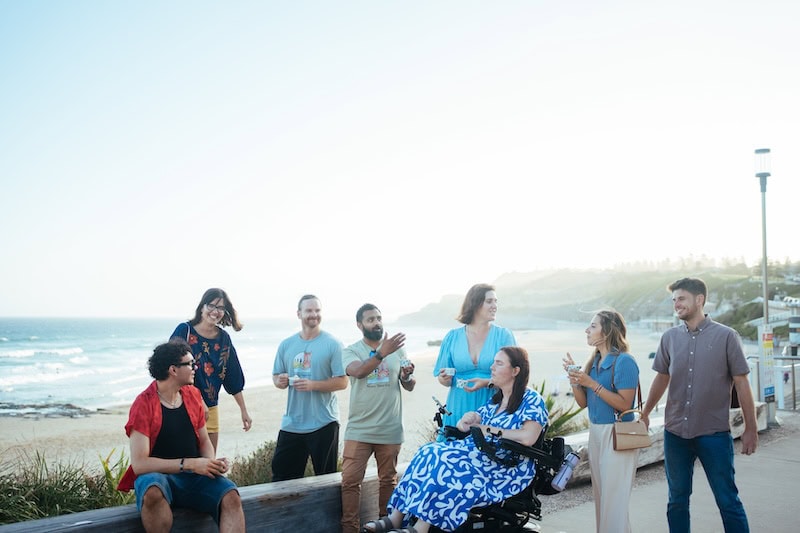 Group of diverse tourists enjoying a guided food and street art tour along Newcastle's scenic waterfront.