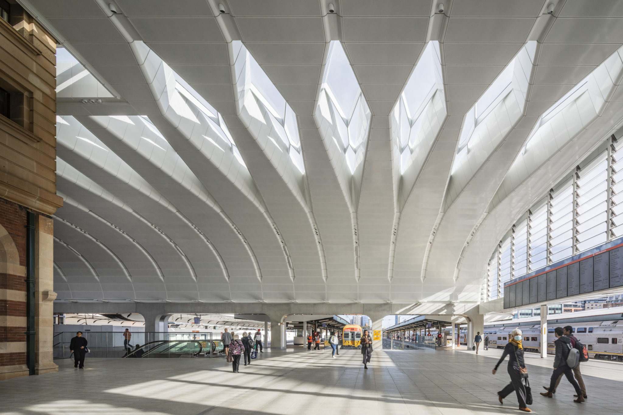 Modern Newcastle train station featuring sleek architecture, passengers, and trains, showcasing transportation hub facilities in Newcastle, Australia.