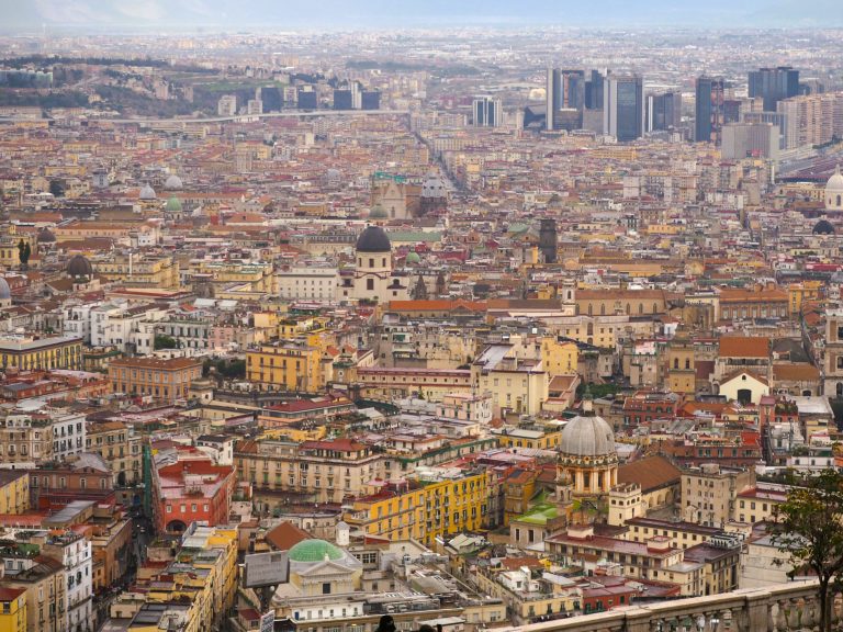 Aerial view of Naples, Italy, with colorful buildings, domes, and modern skyscrapers—perfect for planning the best day trips from Naples to explore the surrounding beauty.