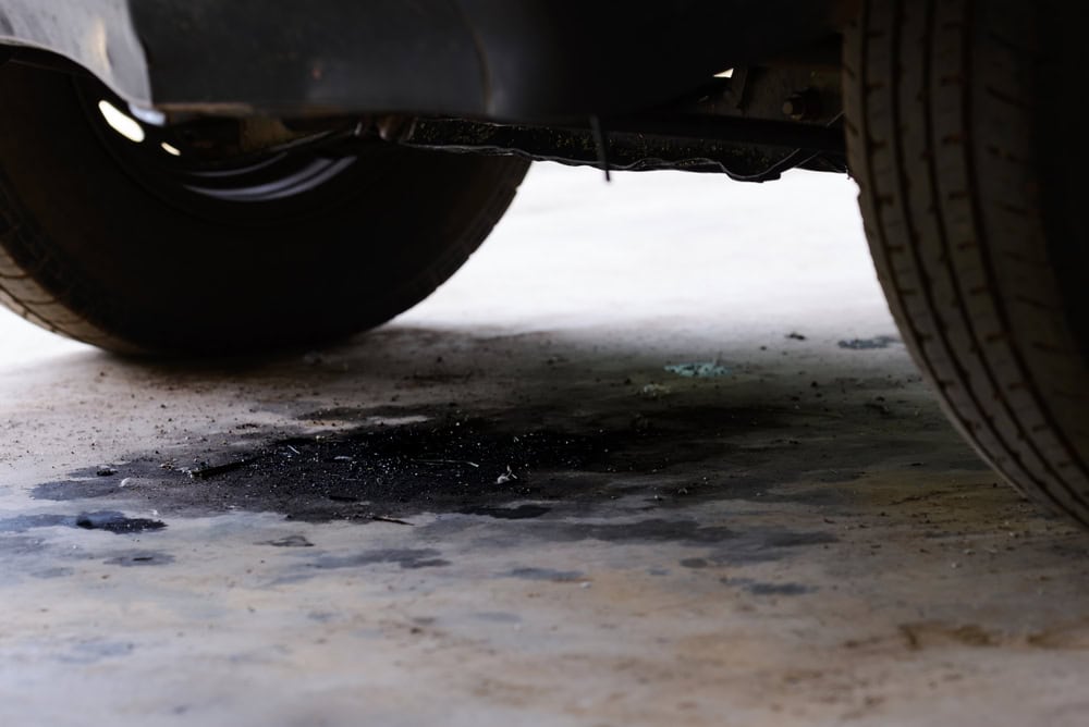 A car leak leaves a dark stain on the garage floor.