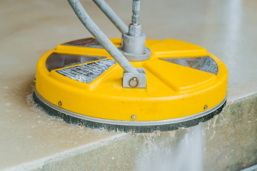 High-powered surface cleaner scrubbing a concrete floor.