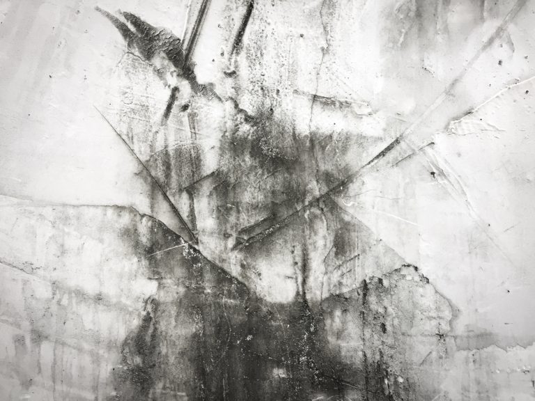 Abstract texture of weathered, cracked concrete in black and white.