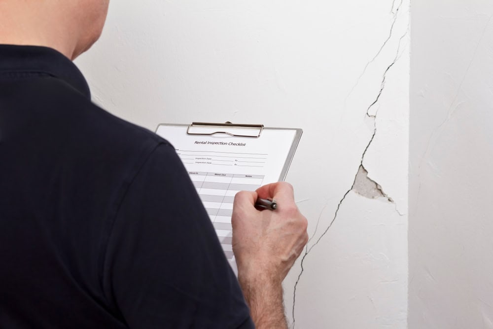 Noting the damage: A property inspector documents wall cracks during a rental inspection.
