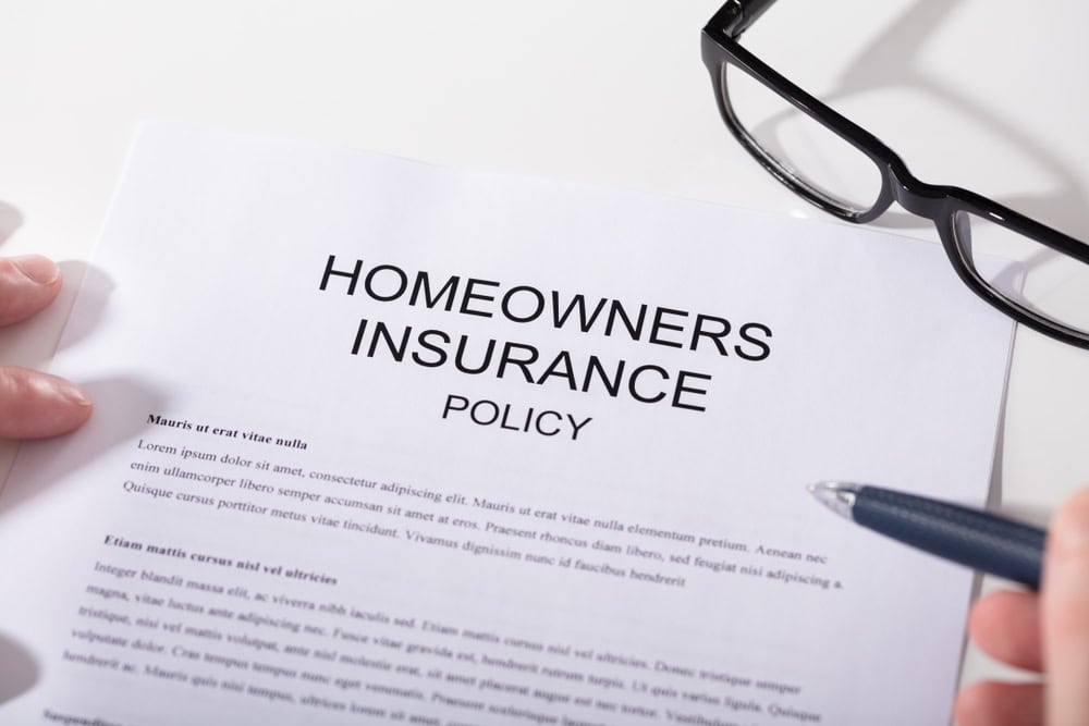 A homeowners insurance policy document with a pen and glasses resting on it.