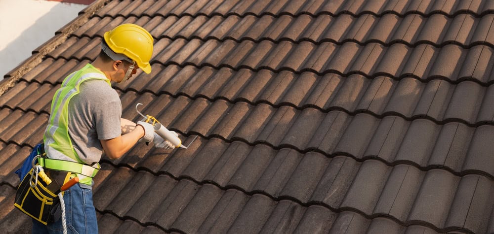 A roofer diligently works on installing tiles, ensuring a sturdy and weatherproof roof.