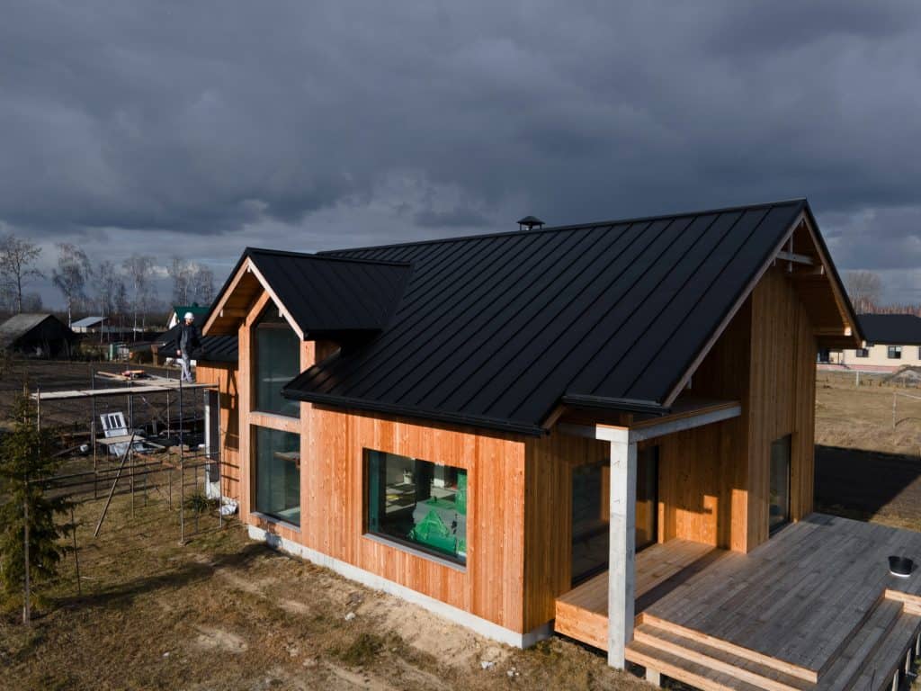 A modern wooden home stands resilient under a moody sky, as construction progress brings it closer to completion.