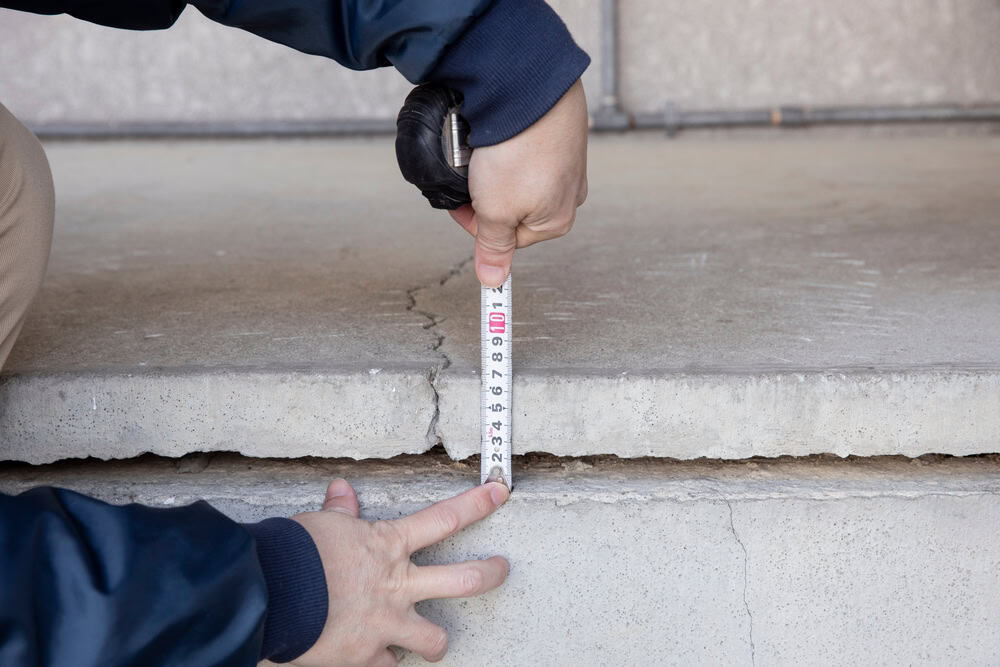 Measuring the crack in the concrete steps for safety assessment.