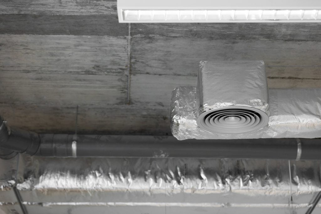 Aluminum foil-wrapped air vent and exposed ductwork in an industrial or basement ceiling
