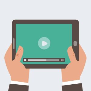Hands holding a tablet displaying a video player interface with a play button and progress bar on a green background