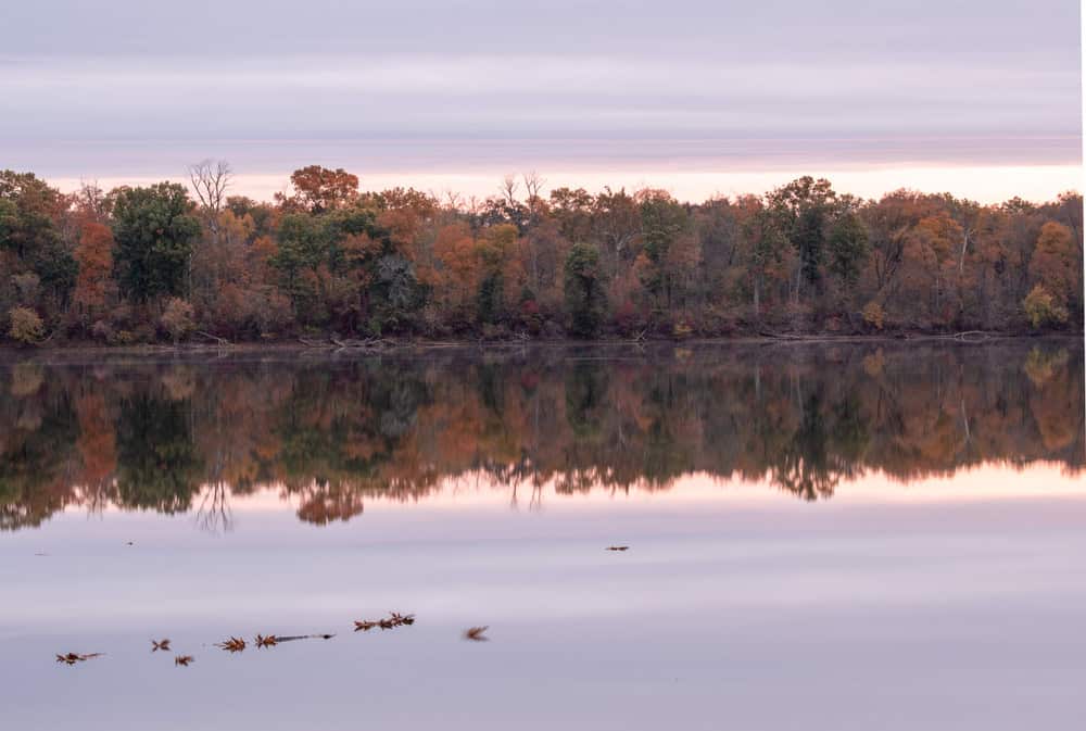 Autumn's reflection: a tranquil lake mirroring fiery trees.