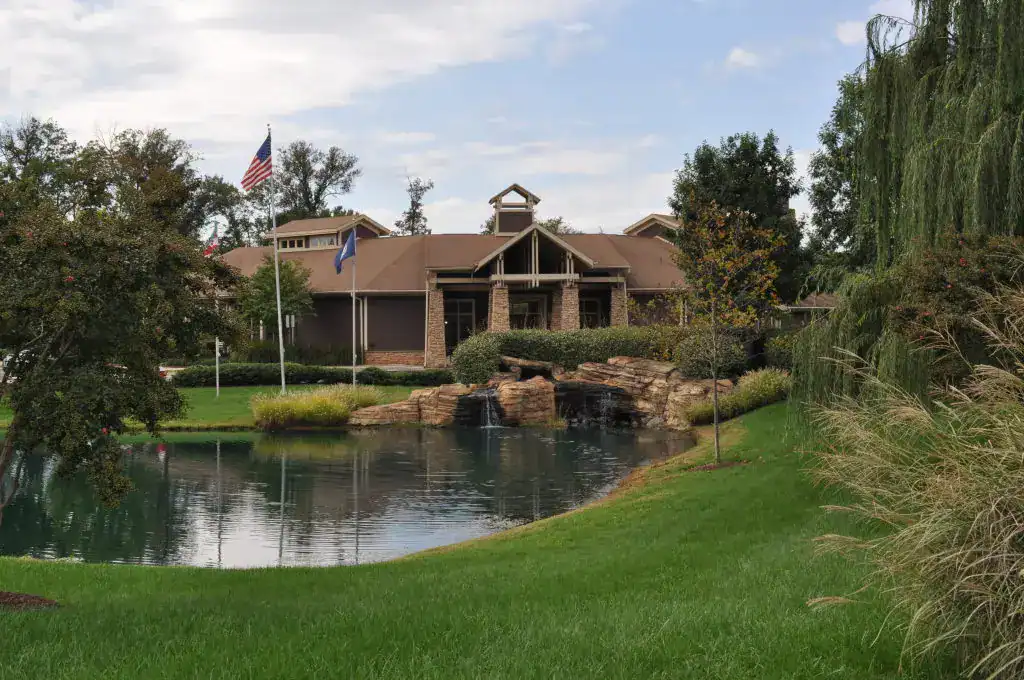 Rustic lodge retreat: A serene oasis with a tranquil pond, cascading waterfall, and lush landscaping, adorned with American and state flags flying proudly.
