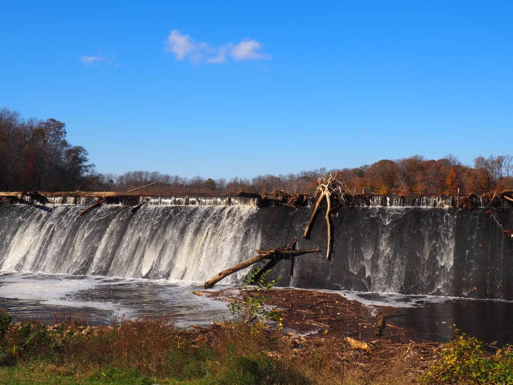 Nature's Power Unleashed: Autumn Waterfall Cascades Over Weathered Dam