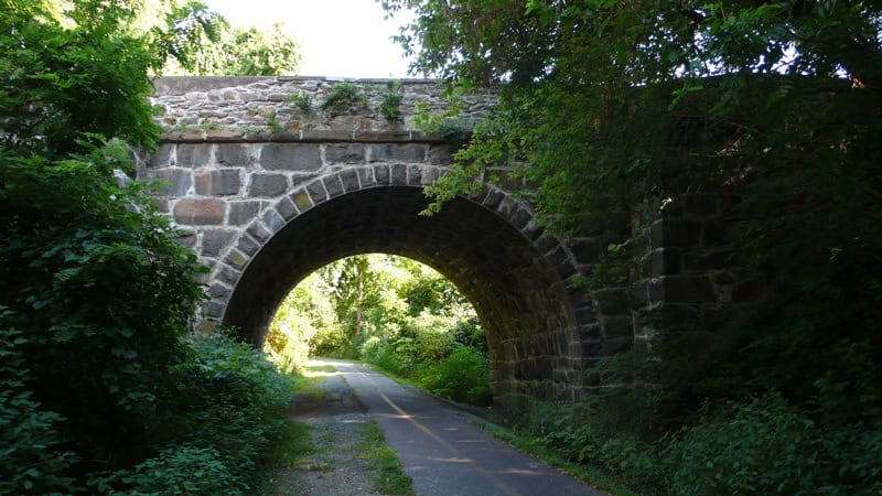 Nature's Gateway: A Stone Arch Bridge Frames a Sunlit Path