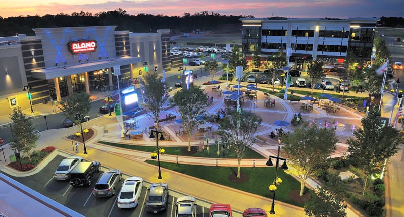 Twilight at the Plaza: Alamo Theater and bustling outdoor shopping center come alive with colorful lights and evening activity.