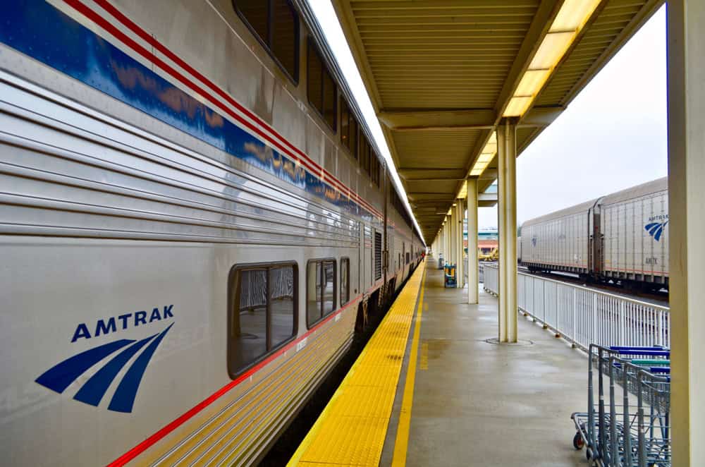 Amtrak's Silver Service: A sleek passenger train awaits departure on a quiet platform, its iconic logo and striping gleaming under the station's fluorescent lights.