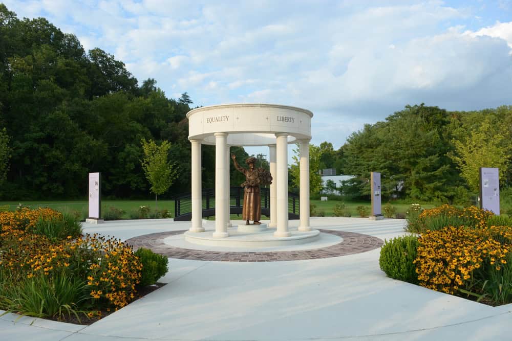 Equality and Liberty: A monument honors a pioneering figure beneath a classical pavilion, surrounded by vibrant gardens and informational displays.