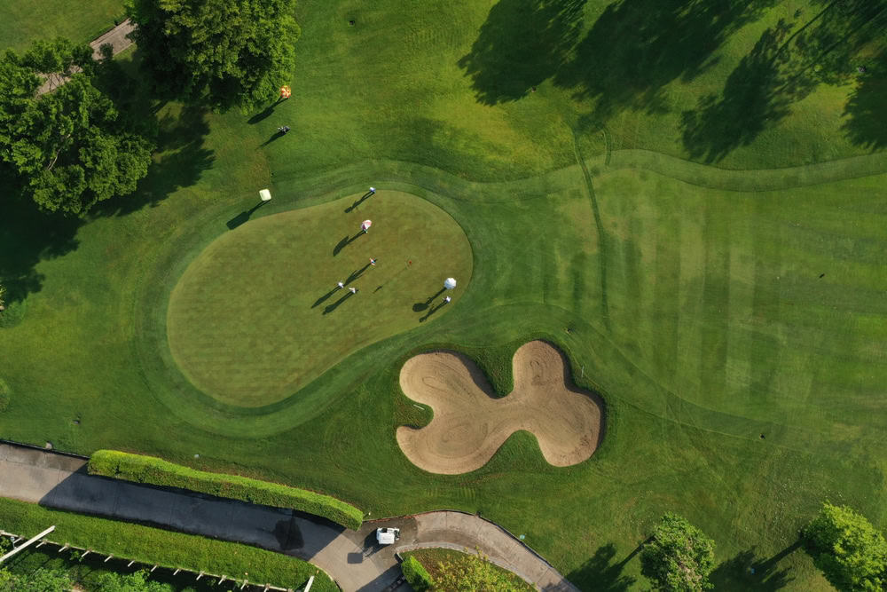 Aerial view of golfers on a lush green course.