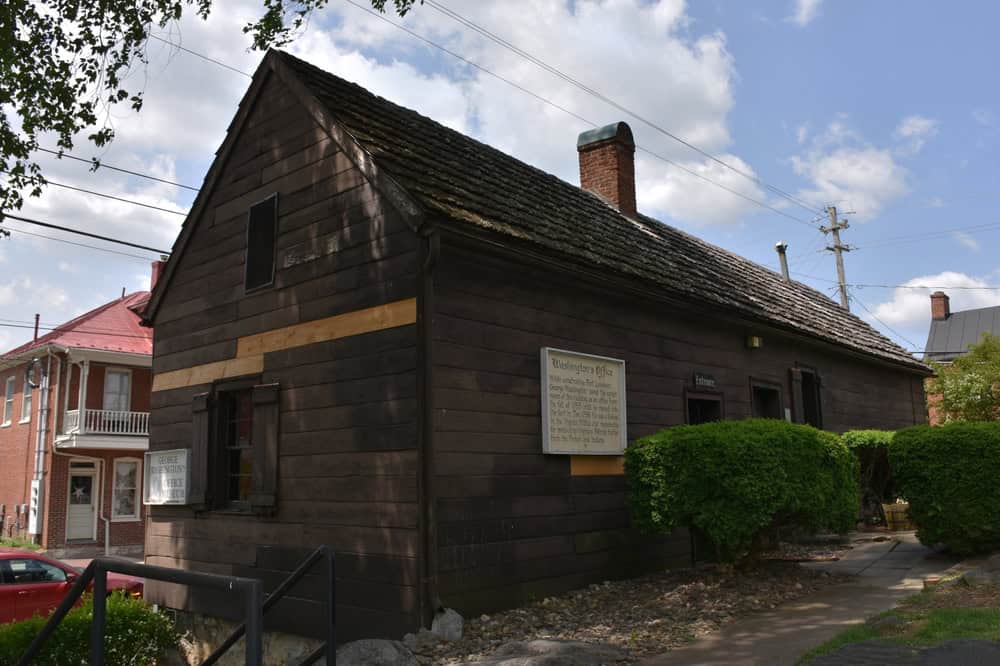 Historic Washington's Office: Rustic wooden structure where George Washington once worked, now preserved amidst modern surroundings.