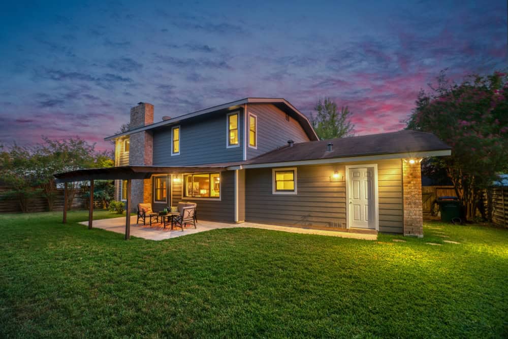Serene twilight at a beautiful two-story suburban home with a cozy backyard patio.