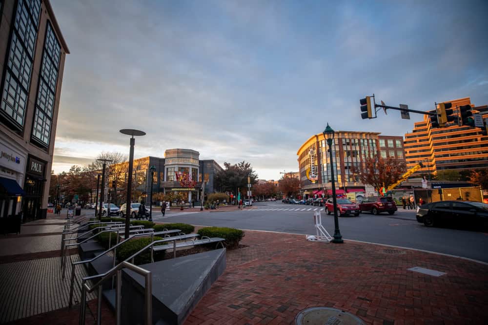 Dusk settles over Bethesda Row in Maryland, as the evening light illuminates the urban streetscape of this upscale shopping and dining district, with its characteristic brick sidewalks and modern architecture.