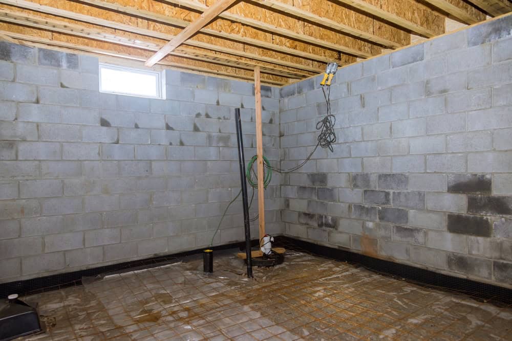 Unfinished basement with exposed cinder block walls and construction materials.